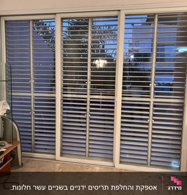 תריסים לבנים על חלון זכוכית גדול בסלון